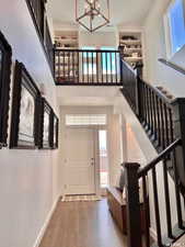 Foyer featuring a healthy amount of sunlight, an inviting chandelier, a high ceiling, and wood-type flooring