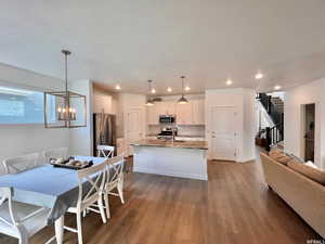 Dining room with a textured ceiling, an inviting chandelier, sink, and wood-type flooring