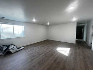 Empty room with dark wood-type flooring and a textured ceiling