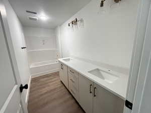 Bathroom featuring wood-type flooring,  shower combination, a textured ceiling, and vanity