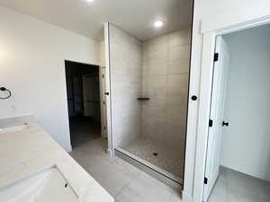 Bathroom featuring vanity, tile patterned flooring, and a tile shower