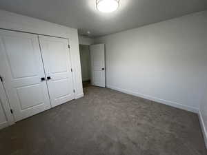 Unfurnished bedroom featuring a closet and dark colored carpet