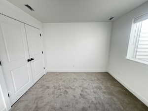 Unfurnished bedroom with light colored carpet and a closet