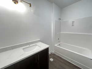 Bathroom featuring hardwood / wood-style flooring, vanity, and shower / bath combination