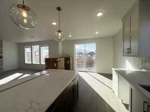 Kitchen featuring tasteful backsplash, hanging light fixtures, and light stone countertops