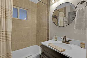 Bathroom featuring vanity and shower / bathtub combination with curtain