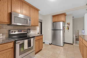 Kitchen with tasteful backsplash, light tile patterned flooring, and stainless steel appliances