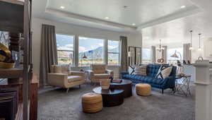 Carpeted living room featuring a mountain view, a textured ceiling, an inviting chandelier, and a tray ceiling