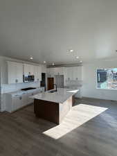 Kitchen featuring sink, white cabinets, black gas cooktop, and an island with sink