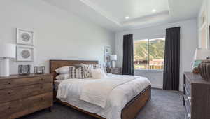 Bedroom featuring a raised ceiling and dark colored carpet