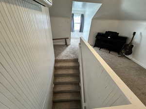 Staircase featuring a wall mounted AC and carpet floors