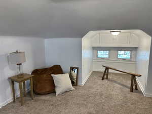 Living area with carpet floors and vaulted ceiling