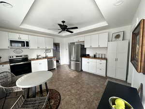 Kitchen featuring a raised ceiling, appliances with stainless steel finishes, and wood counters