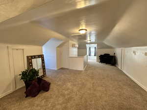 Additional living space with vaulted ceiling and carpet flooring