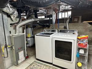 Clothes washing area featuring separate washer and dryer and secured water heater