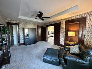 Interior space with ceiling fan, light carpet, and a raised ceiling