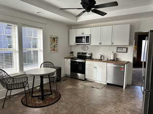 Kitchen featuring ceiling fan, sink, appliances with stainless steel finishes, white cabinets, and butcher block counters