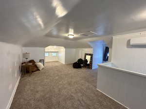 Additional living space with carpet, lofted ceiling, and a wall mounted air conditioner