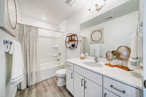 Full bathroom featuring toilet, vanity, hardwood / wood-style floors, and shower / bath combo with shower curtain