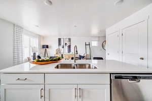 Kitchen with stainless steel dishwasher, white cabinetry, and sink