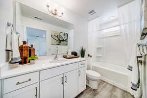 Full bathroom with bathing tub / shower combination, hardwood / wood-style floors, vanity, and toilet