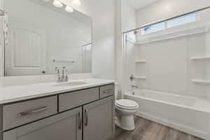 Full bathroom with hardwood / wood-style floors, vanity, toilet, and shower / tub combination