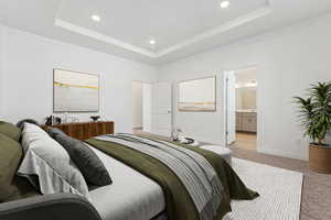 Carpeted bedroom featuring connected bathroom and a tray ceiling