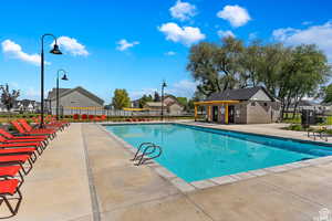 Community pool with a patio, fence, and a residential view