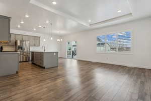 Kitchen featuring pendant lighting, stainless steel appliances, a kitchen island with sink, and gray cabinetry