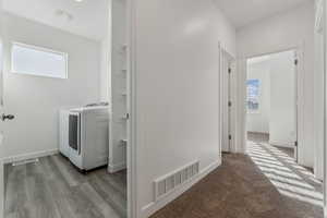 Clothes washing area with washer / dryer and light hardwood / wood-style flooring