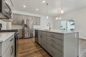 Kitchen with gray cabinetry, sink, decorative light fixtures, a kitchen island with sink, and appliances with stainless steel finishes