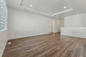 Spare room with a raised ceiling, wood-type flooring, and a textured ceiling