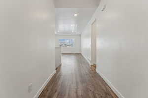 Hallway with a raised ceiling, a textured ceiling, and dark wood-type flooring