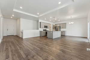 Kitchen with appliances with stainless steel finishes, pendant lighting, gray cabinets, and a center island with sink