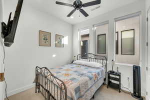 Carpeted bedroom with ceiling fan and heating unit