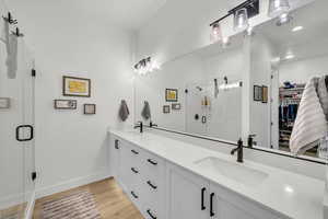 Bathroom with a shower with door, vanity, and hardwood / wood-style flooring