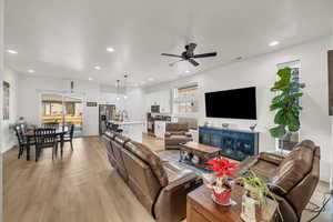 Living room with ceiling fan, light wood-type flooring, and sink