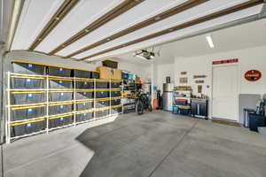 Garage featuring a garage door opener and stainless steel refrigerator