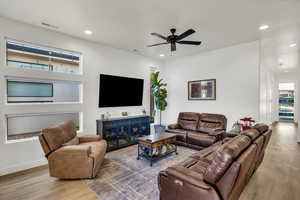 Living room featuring hardwood / wood-style floors, ceiling fan, and a healthy amount of sunlight