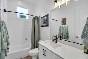 Full bathroom featuring shower / bath combo with shower curtain, vanity, and toilet