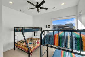 Carpeted bedroom featuring ceiling fan