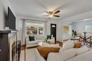 Living room featuring a fireplace, ceiling fan, light hardwood / wood-style floors, and a healthy amount of sunlight