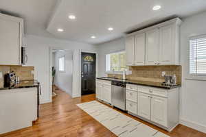 Kitchen with appliances with stainless steel finishes, light wood-type flooring, white cabinets, and sink