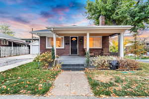 Bungalow-style house featuring covered porch, a lawn, a garage, and an outdoor structure