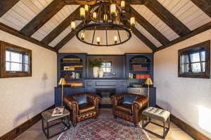 Living area with a notable chandelier, wooden ceiling, built in features, and plenty of natural light