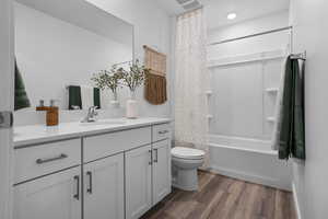 Full bathroom featuring toilet, shower / bath combination with curtain, wood-type flooring, and vanity