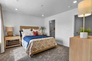 Bedroom featuring connected bathroom and dark colored carpet