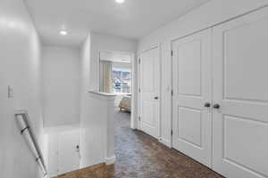 Hallway featuring dark colored carpet