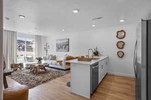 Kitchen featuring hardwood / wood-style floors, white cabinets, stainless steel appliances, kitchen peninsula, and sink