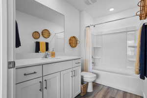 Full bathroom featuring toilet, vanity, shower / bath combination with curtain, and hardwood / wood-style floors